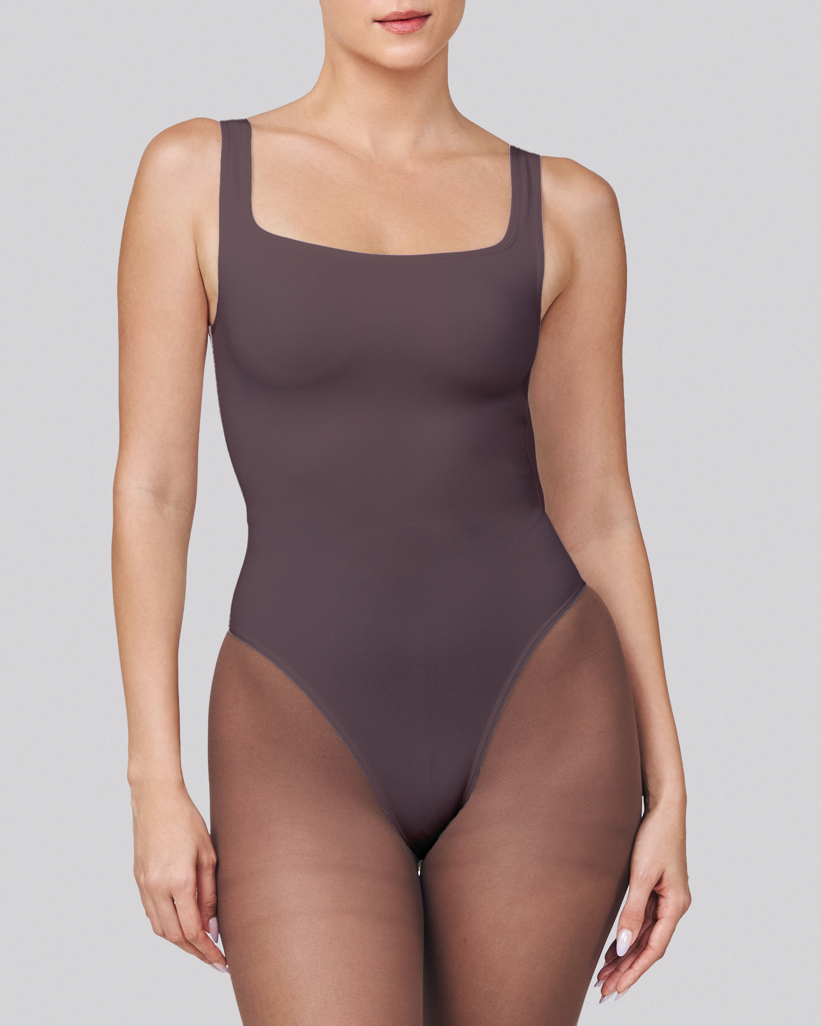 Person wearing a dark brown bodysuit on a light gray background