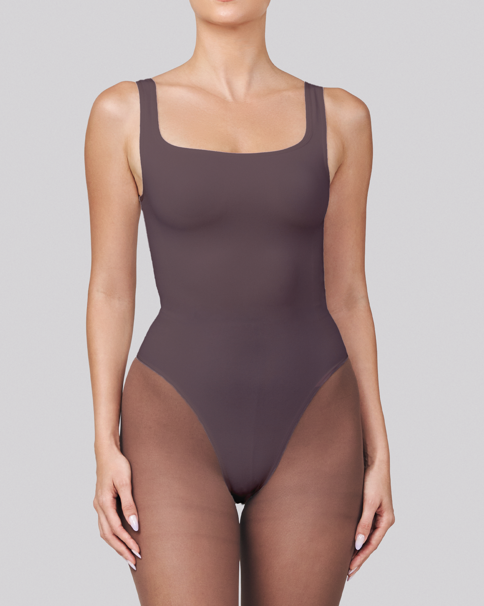 Person wearing a dark brown bodysuit on a gray background