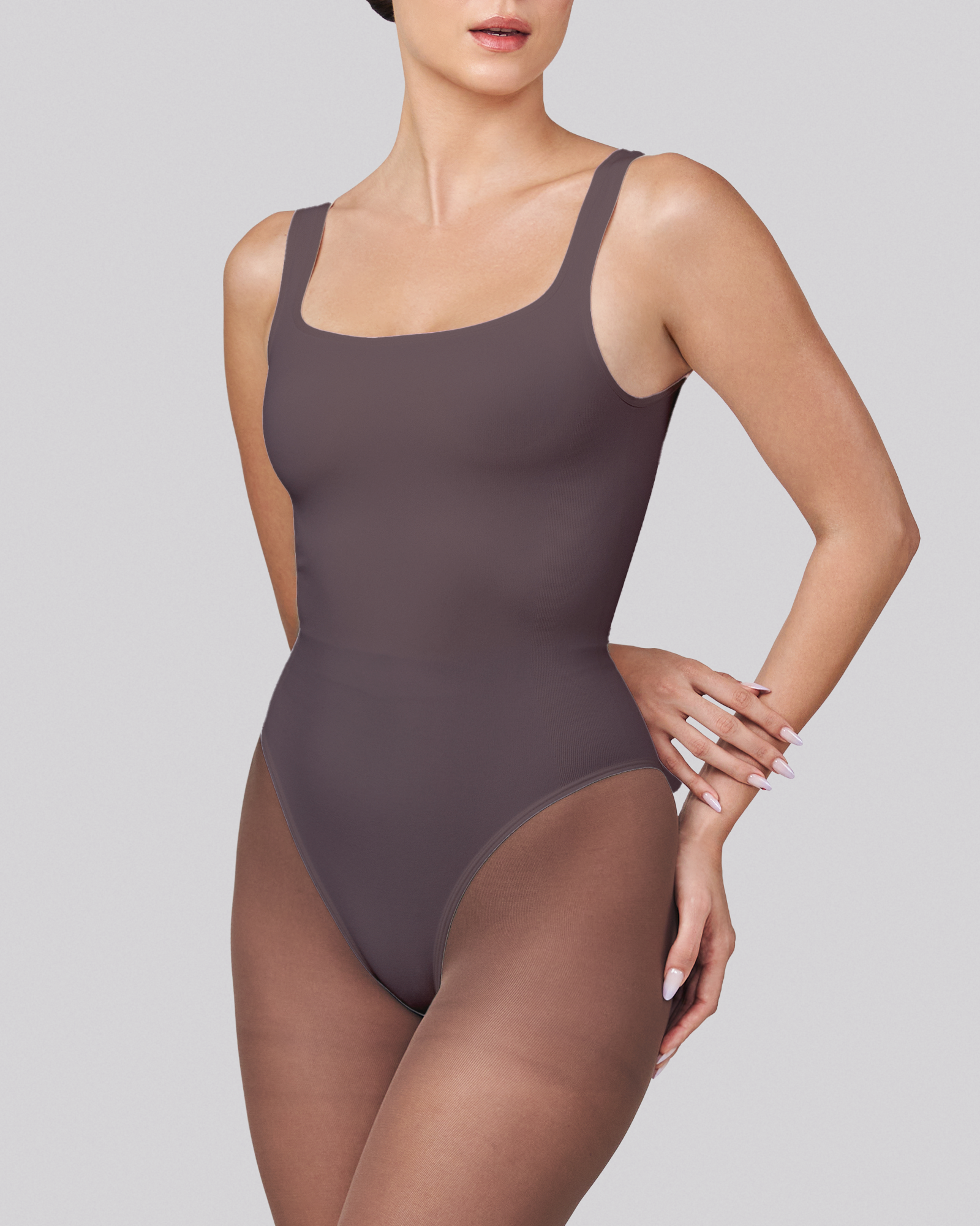 Person wearing a dark gray bodysuit on a light gray background