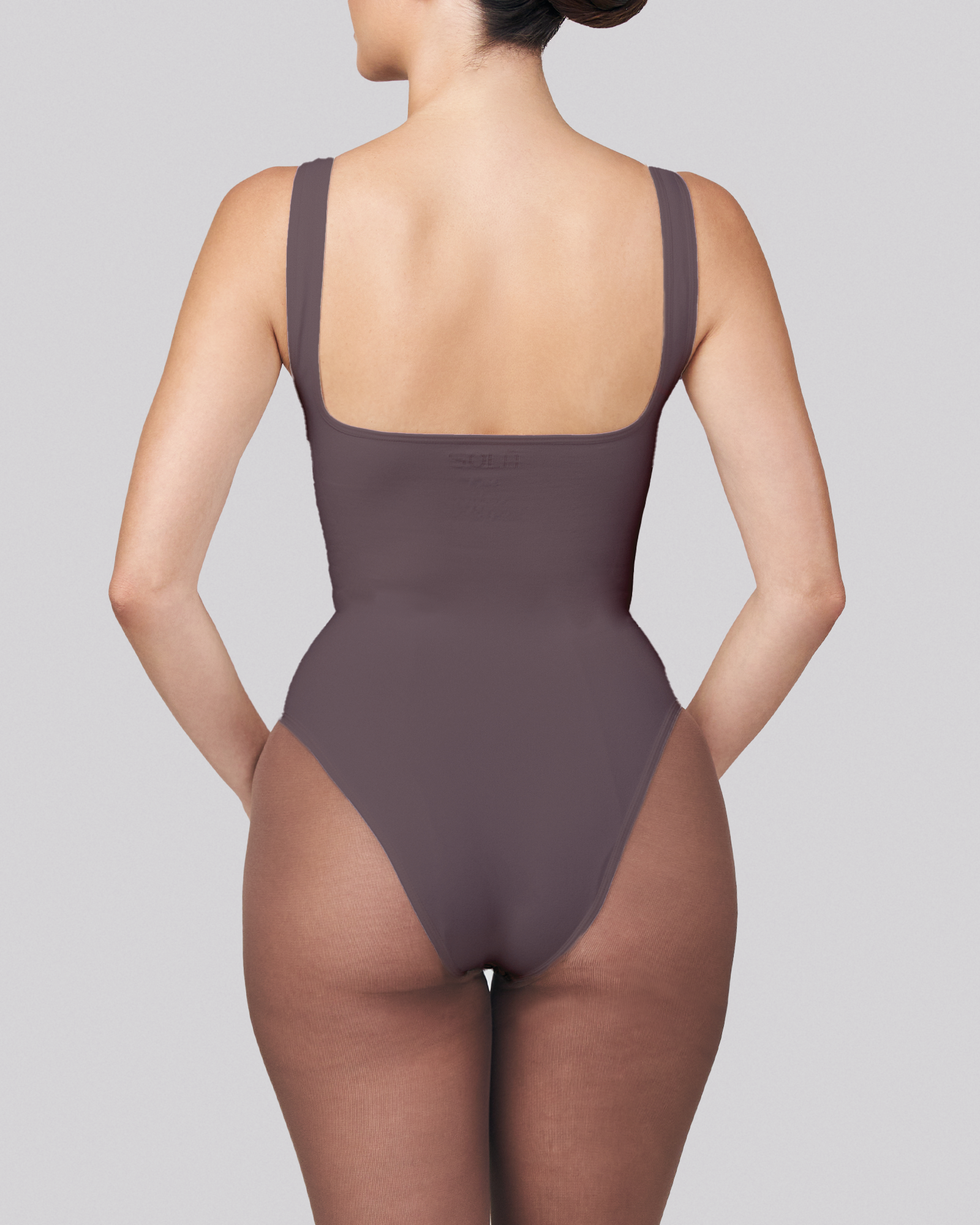 Brown swimsuit worn by a model on a gray background