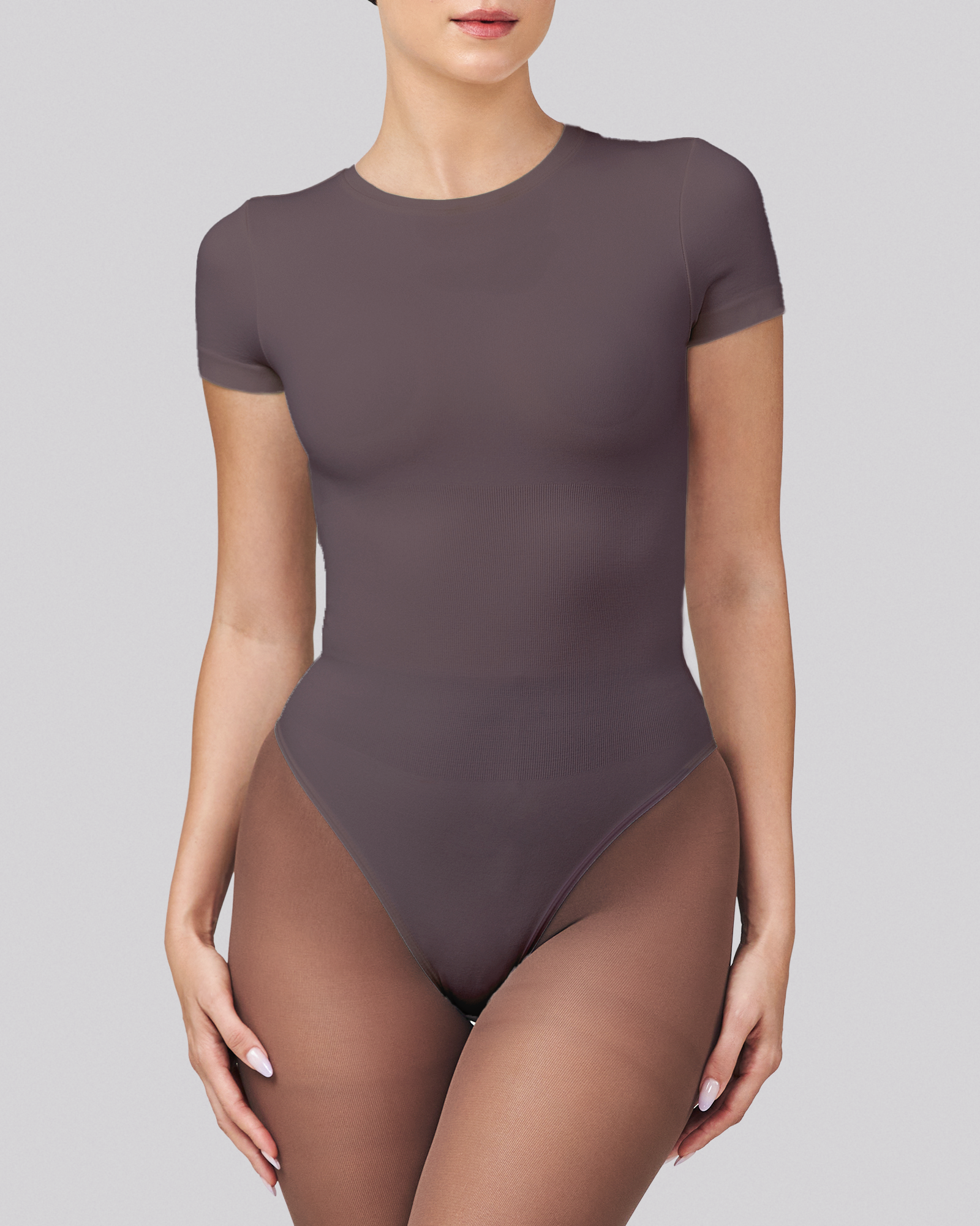 Person wearing a dark gray bodysuit on a light gray background