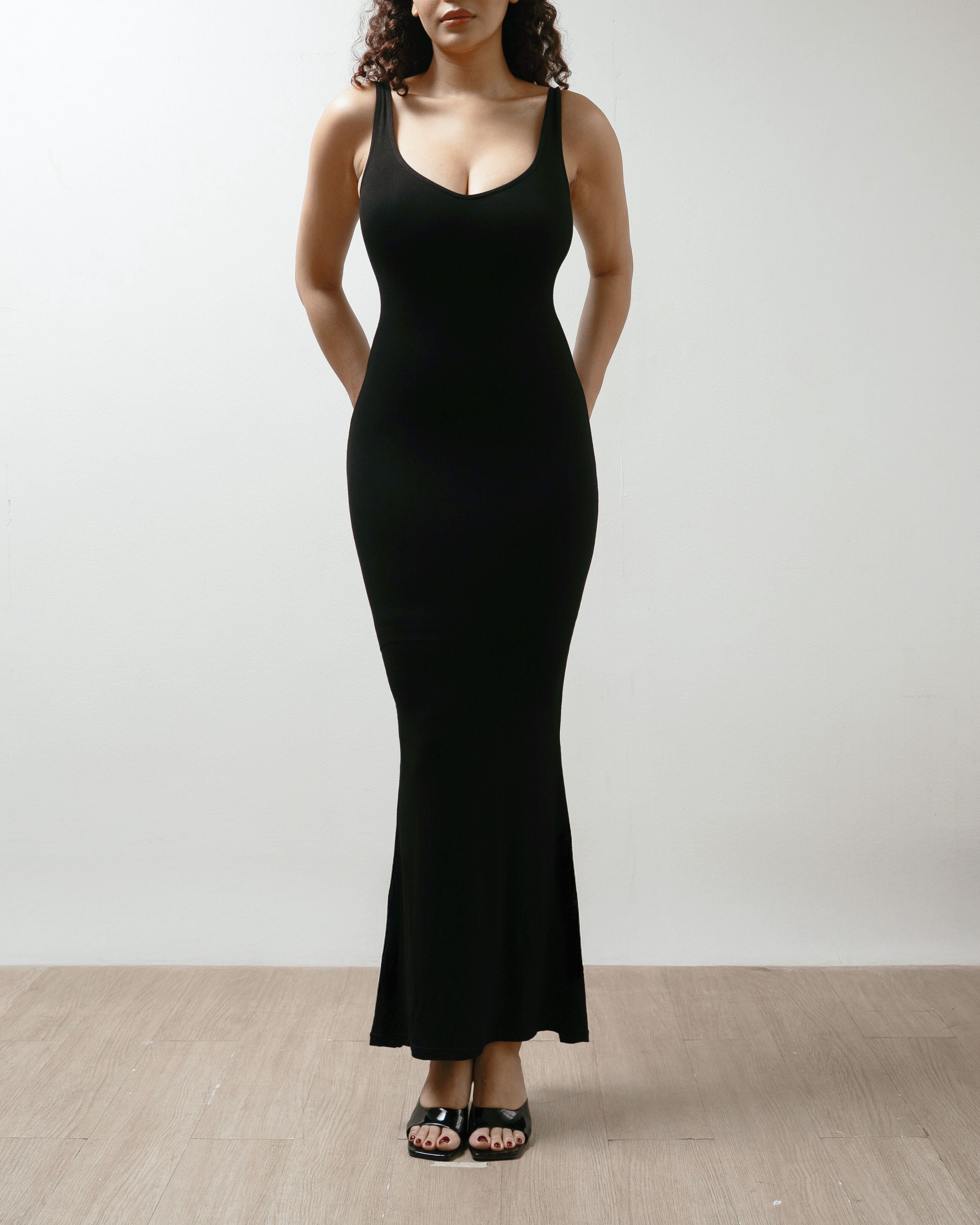 Woman wearing a black dress against a plain background.